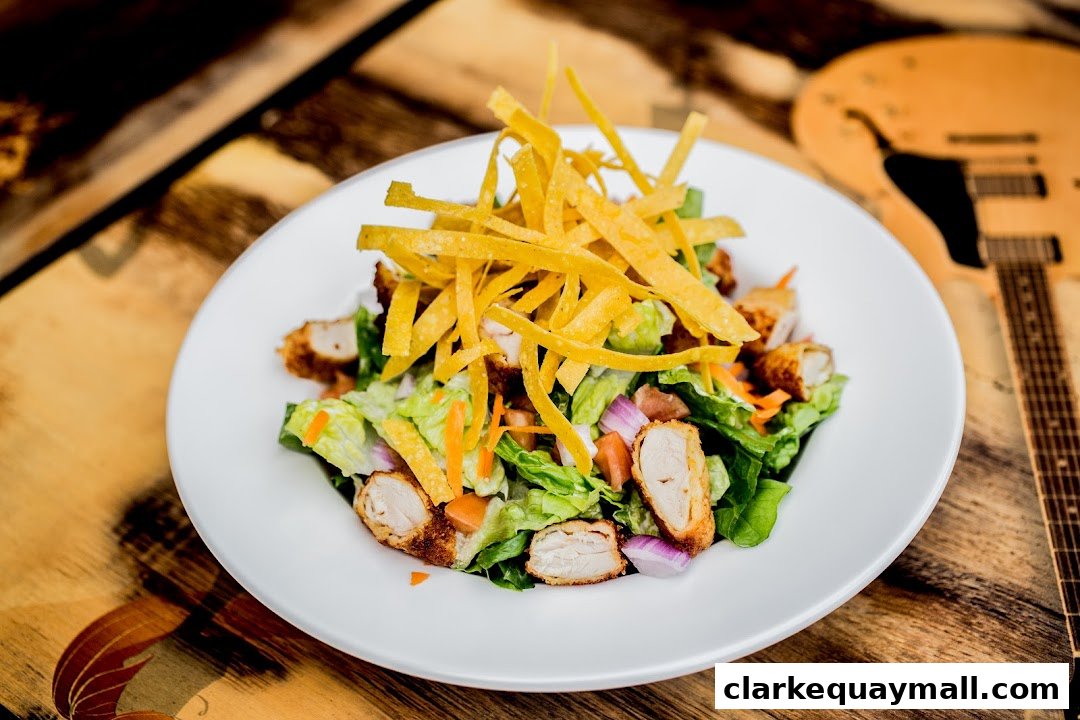 A delicious chicken salad with crispy tortilla strips and fresh vegetables on a white plate.