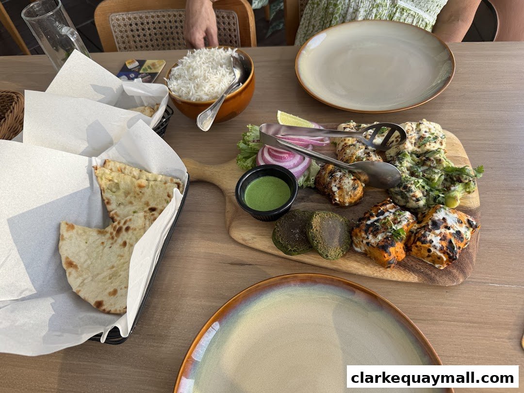 A table setting with a platter of grilled meats, naan bread, rice, and dipping sauce.