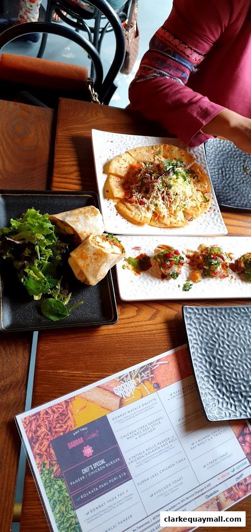 A table at Gabbar Bistro Bar with various Indian dishes and a menu.
