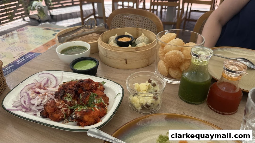 A table laden with Indian dishes including tandoori chicken, momos, and pani puri, with various chutneys and accompaniments.