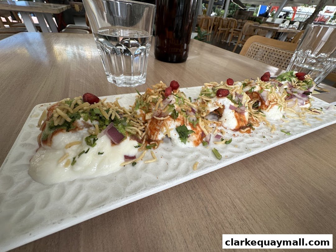 A plate of Indian street food chaat with yogurt, chutneys, and crispy toppings.