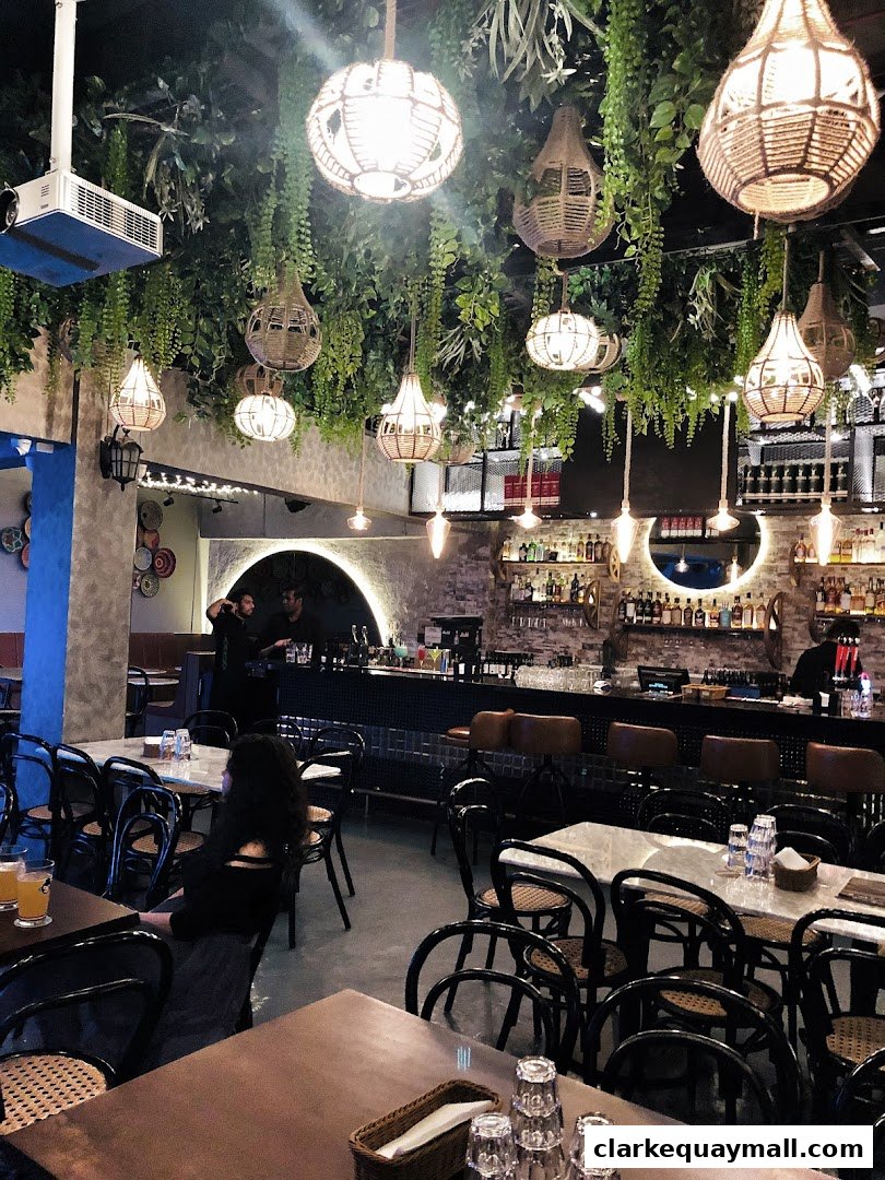 Interior of a stylish bistro with lush greenery and unique pendant lights hanging from the ceiling.