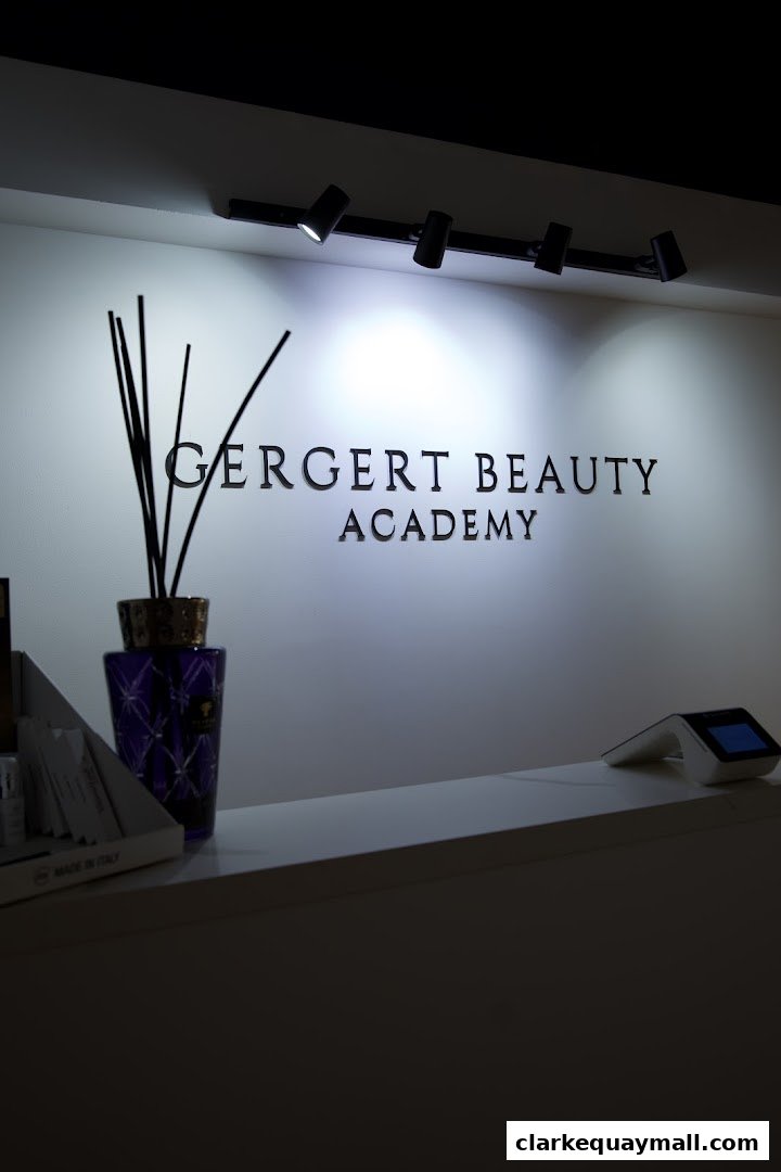 The Gergert Beauty Academy logo is displayed on a wall with decorative reeds and a payment terminal.