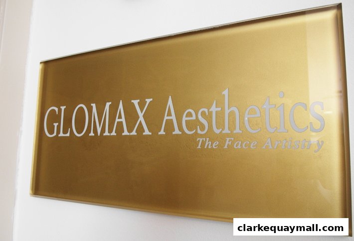 A close-up of a golden sign for Glomax Aesthetics, featuring the tagline 'The Face Artistry'.
