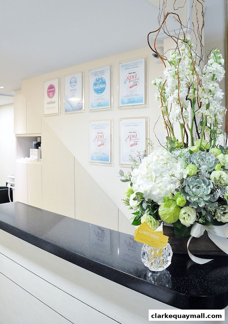 A reception desk with awards and a floral arrangement at Glomax Aesthetics.