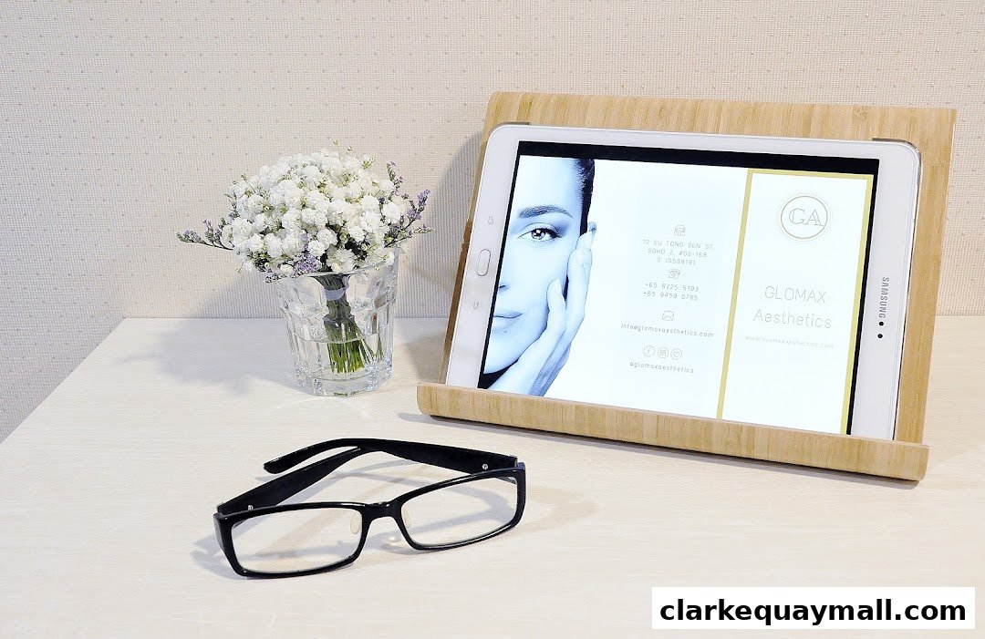 A tablet displaying Glomax Aesthetics information next to a bouquet of flowers and glasses.