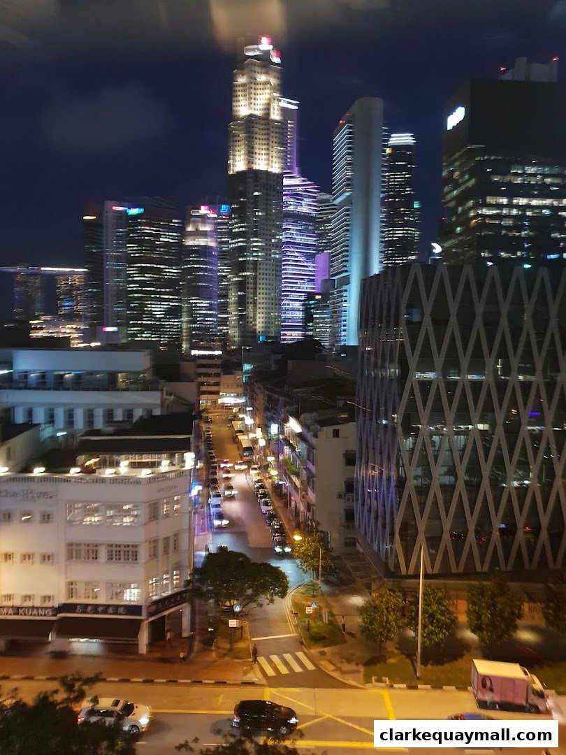 Night view of a city street with illuminated skyscrapers and traffic.