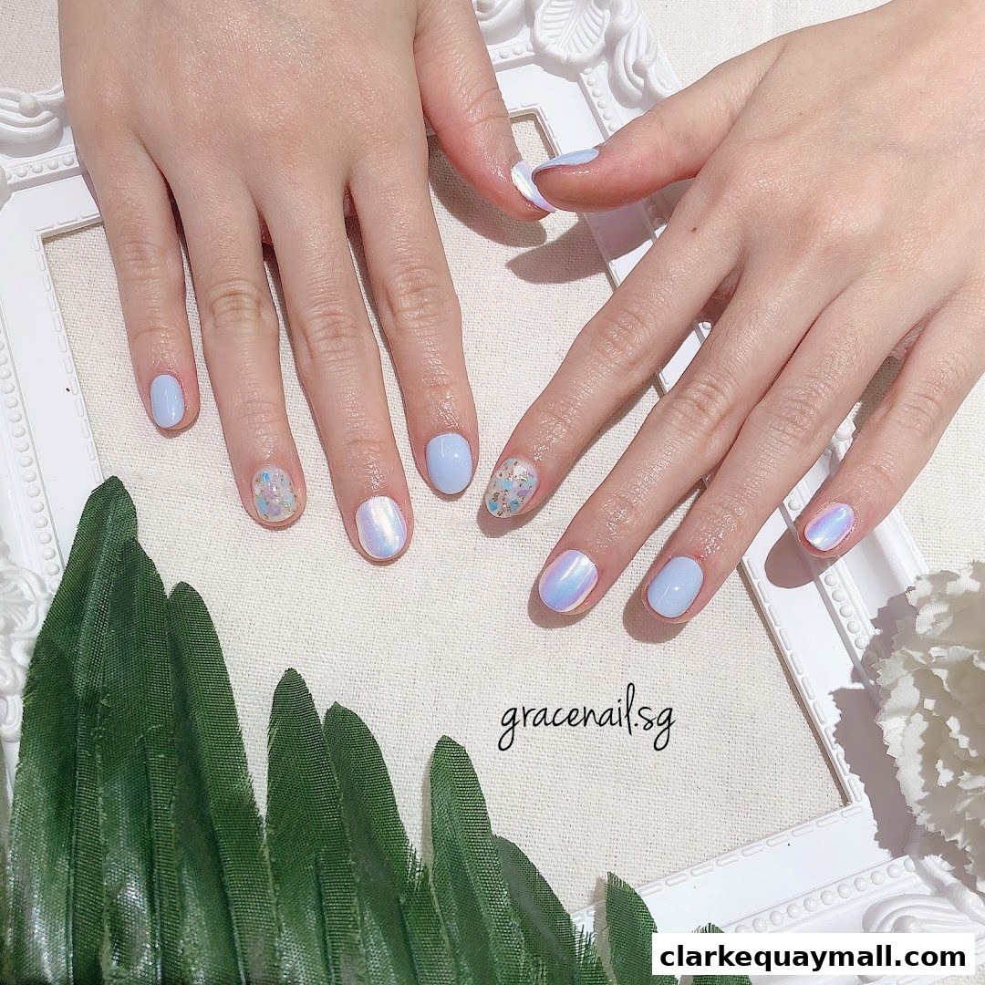 A close-up of hands with light blue and iridescent nail art.