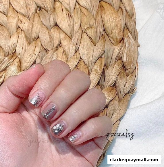A close-up of a hand with elegant, sparkling nail art featuring glitter and pearls.