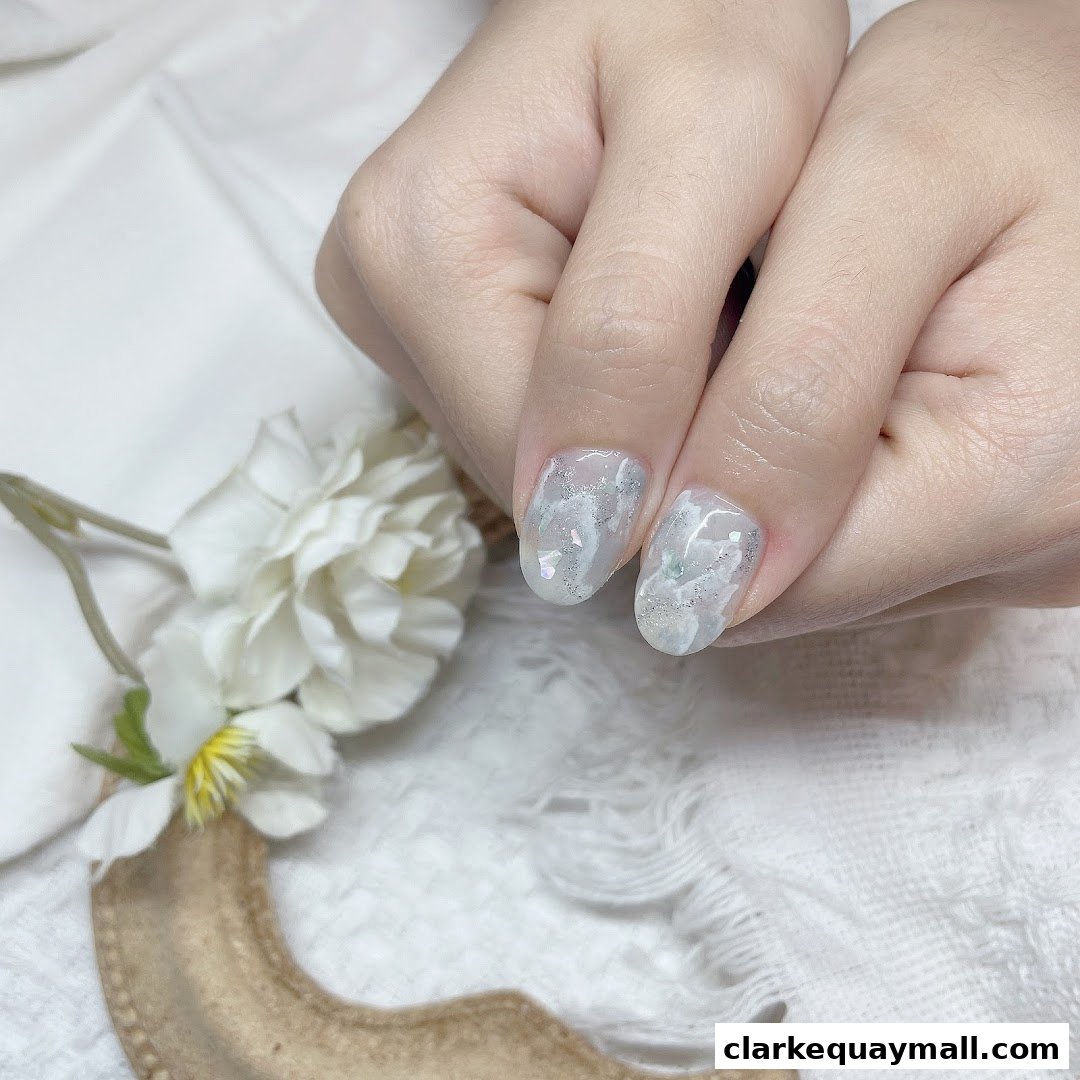 Close-up of hands with elegant marble-patterned nails adorned with glitter.