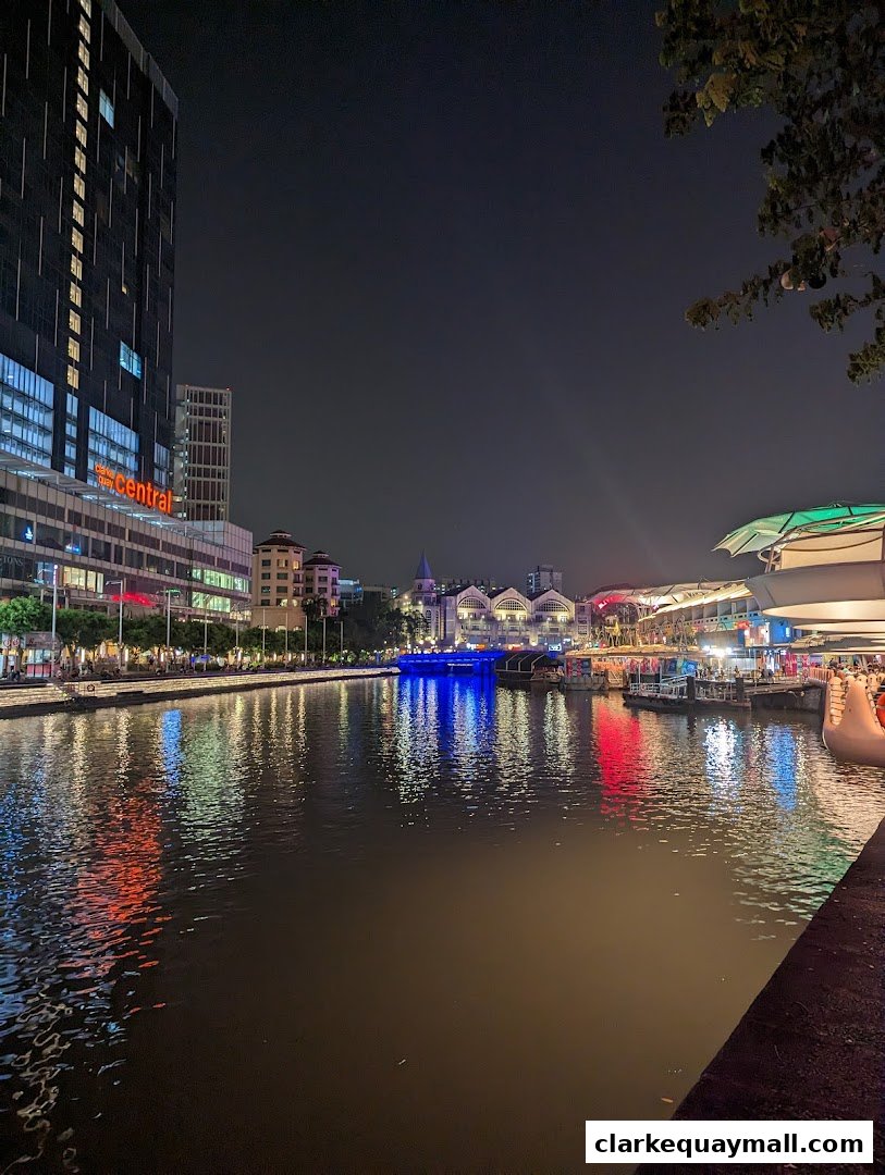 A scenic night view of a riverfront with illuminated buildings and reflections on the water.