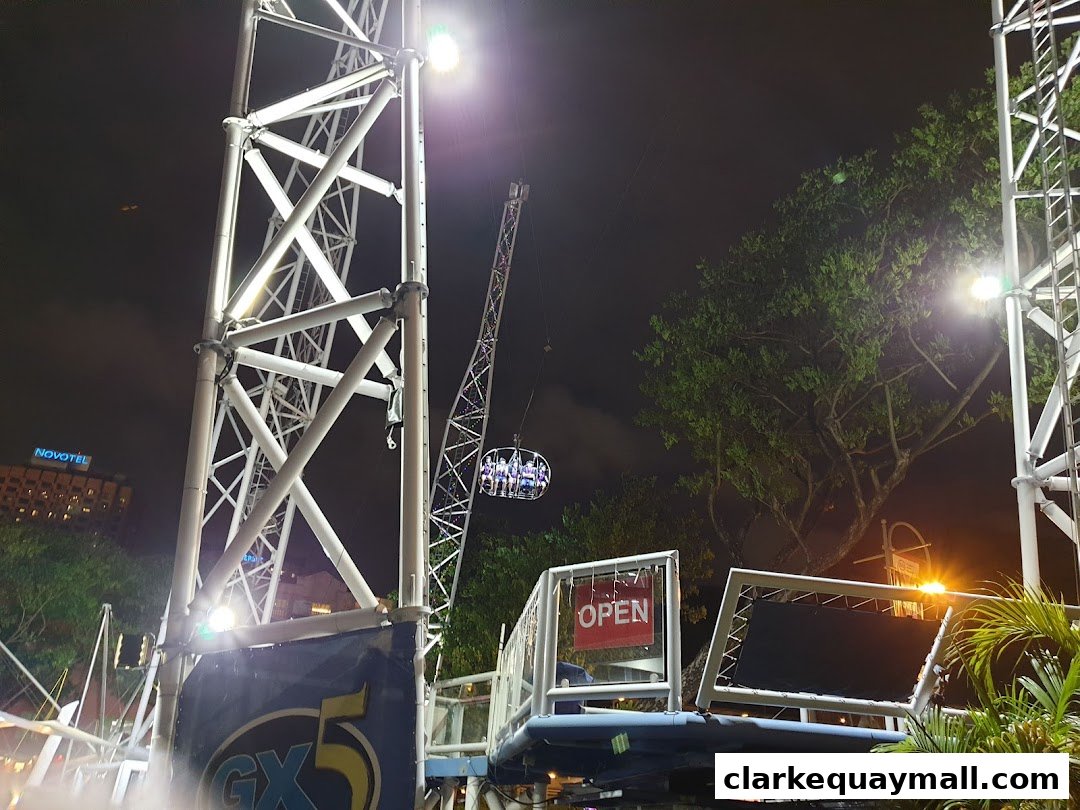 The GX-5 Extreme Swing attraction at night with people in the swing capsule.