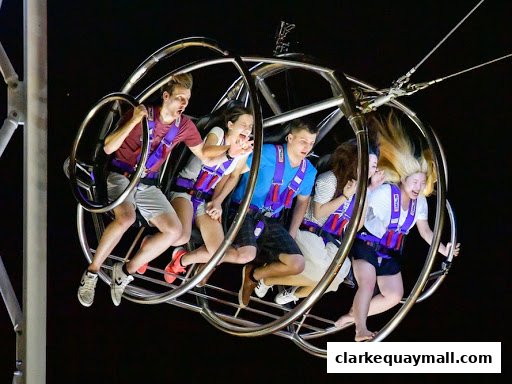 People experiencing the thrill of the GX-5 Extreme Swing ride at night.