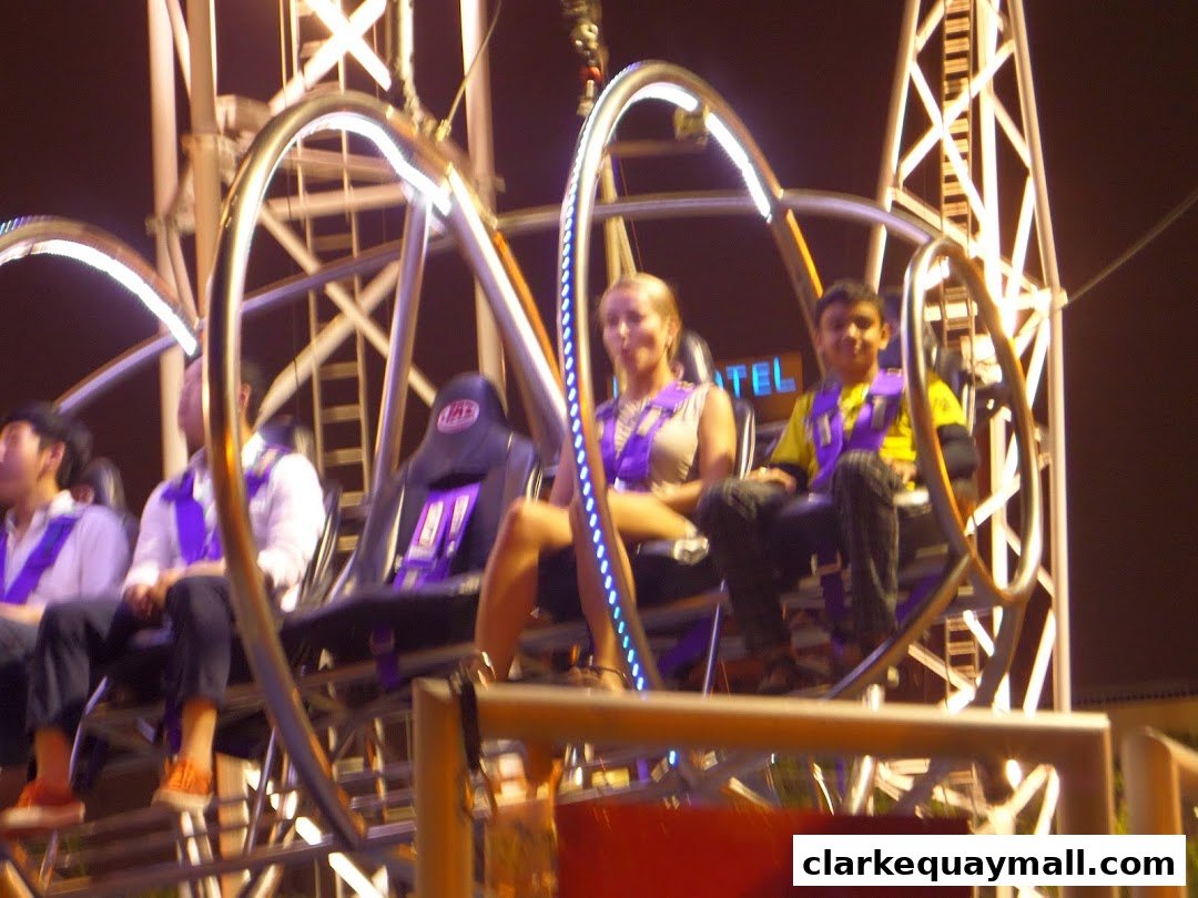 People riding the GX-5 Extreme Swing attraction at night.