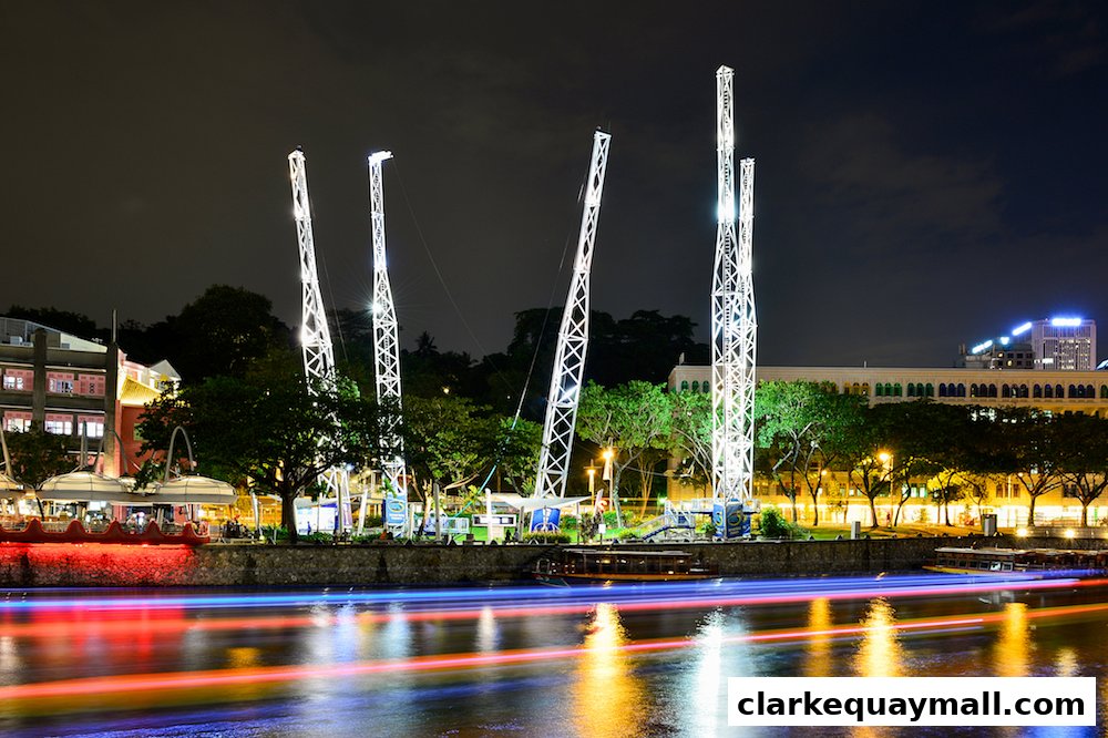 Night view of the GX-5 Extreme Swing attraction with illuminated towers and a river.