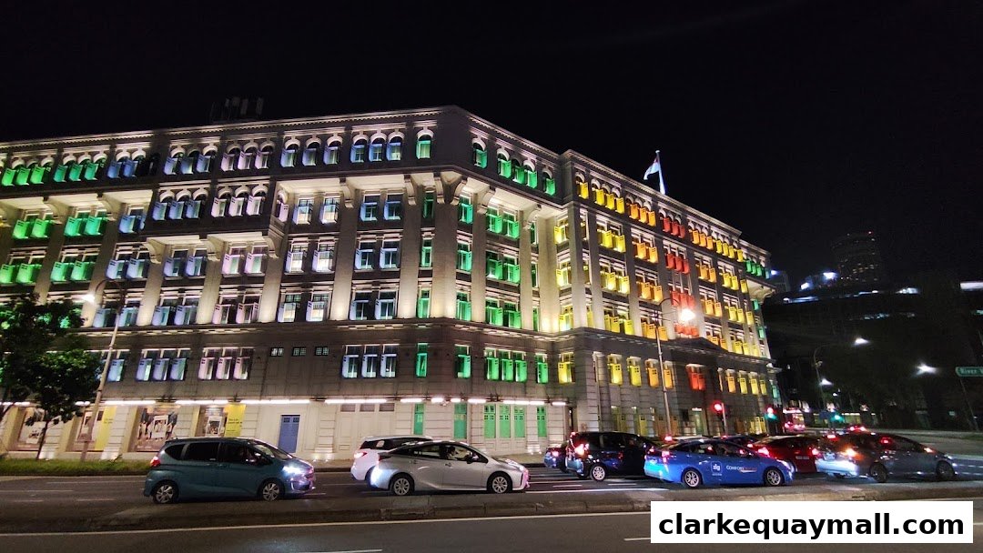 A building illuminated with colorful lights at night, with cars on the street.