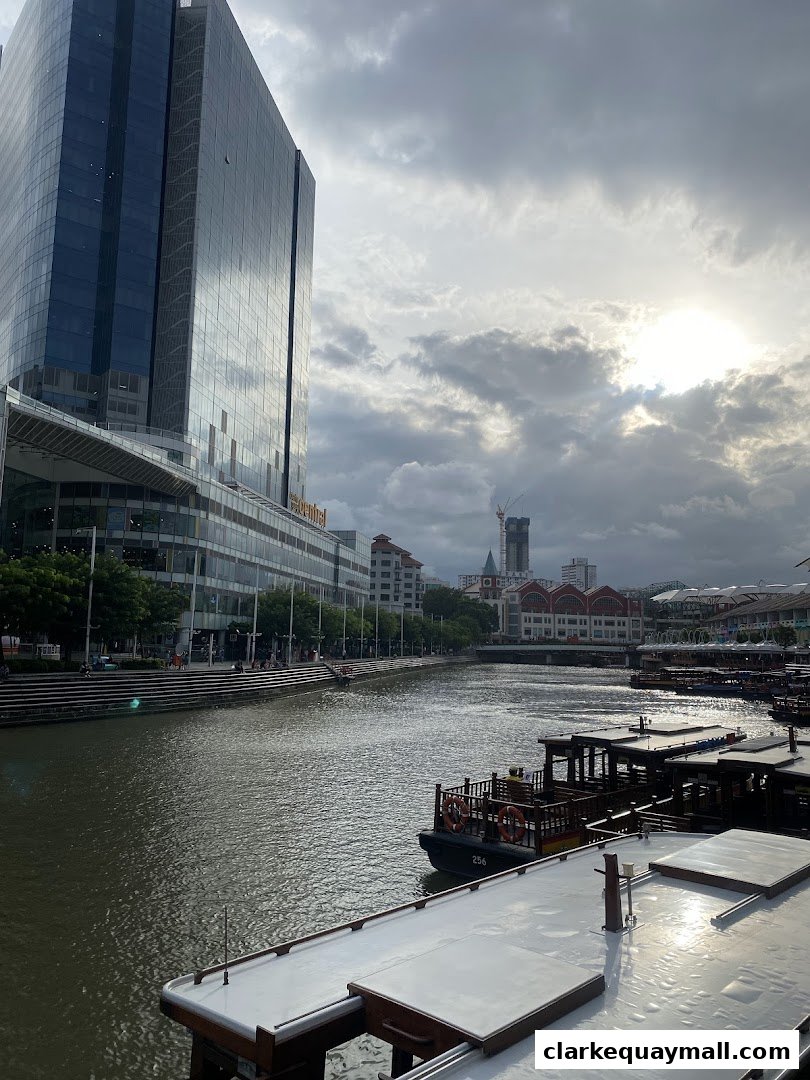 A scenic view of a river with boats docked alongside a modern building and cityscape.