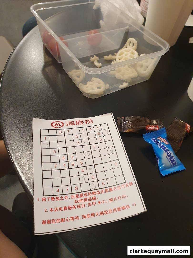 A table with a sudoku puzzle, snacks, and a container of lotus root chips.