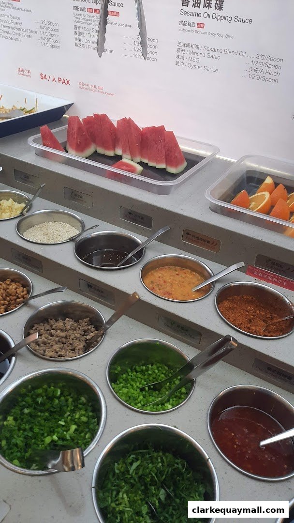 A selection of fresh ingredients and sauces for hot pot, including watermelon and oranges.