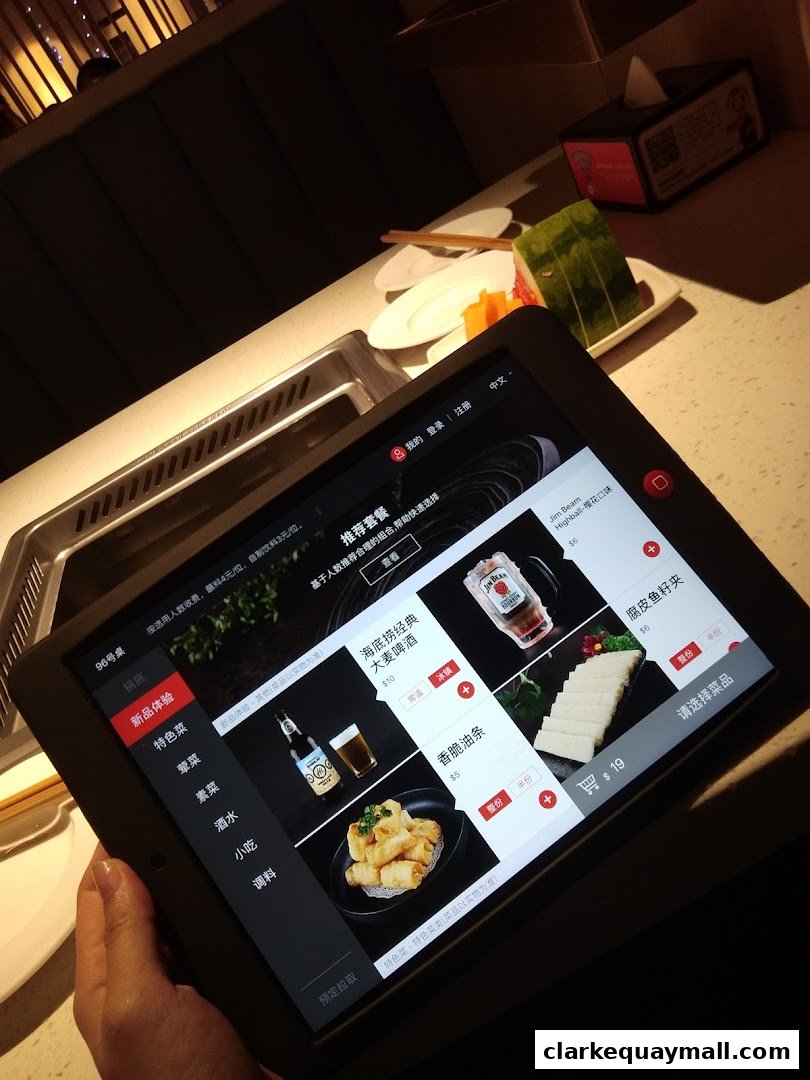 A tablet displays a digital menu for Haidilao Hot Pot, showing various food and drink items.