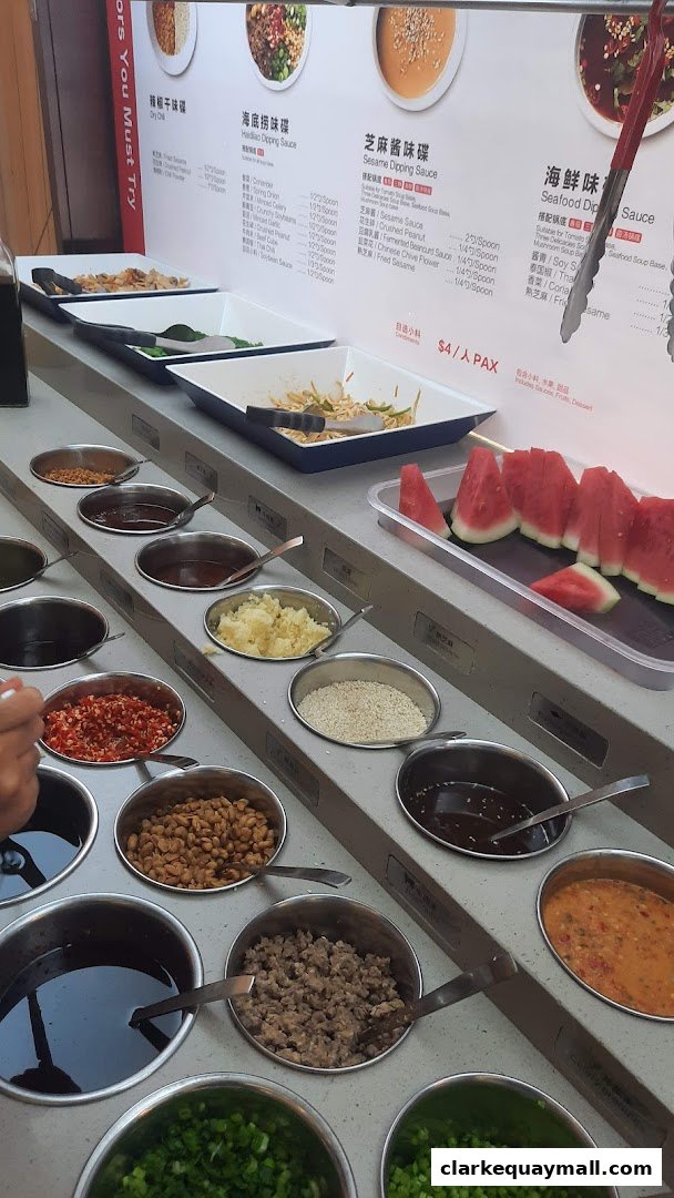 A selection of dipping sauces and condiments for hot pot, with watermelon slices.