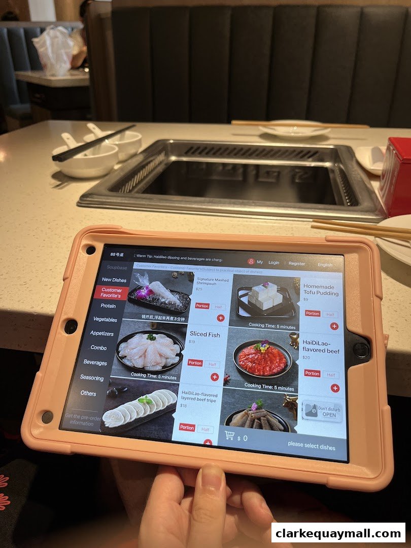 A tablet displays a digital menu for Haidilao Hot Pot, showing various dishes and prices.