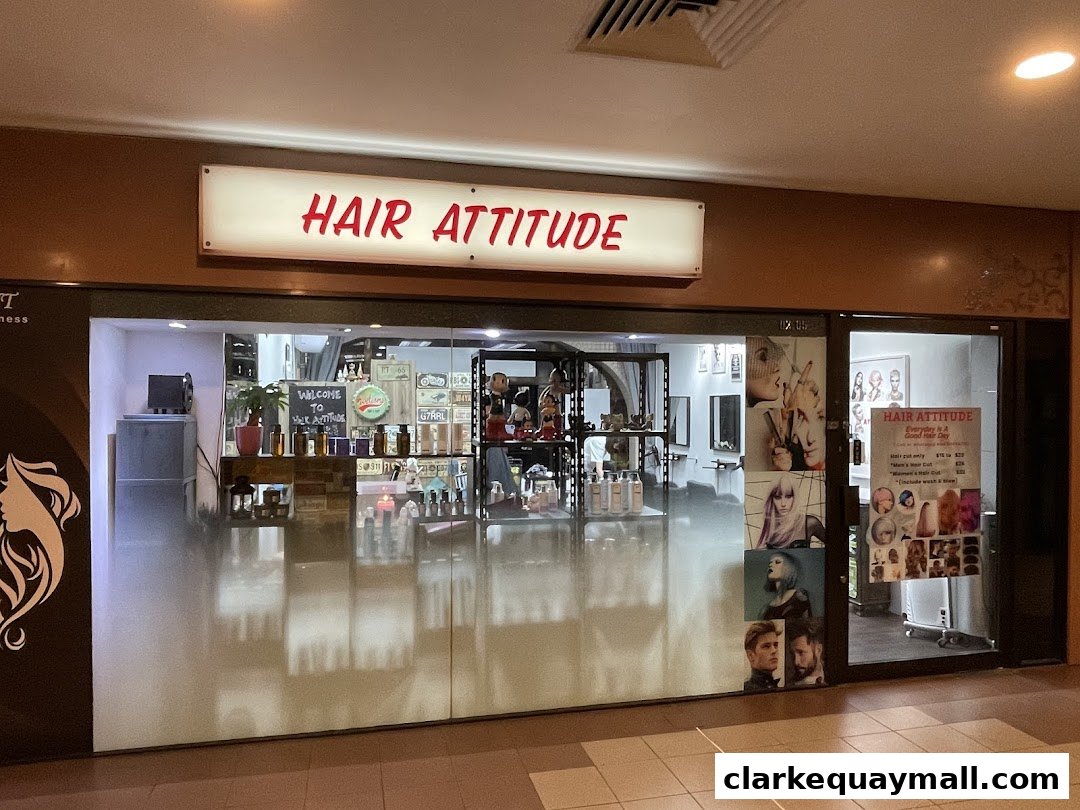 The storefront of Hair Attitude salon, featuring a bright sign and displays of hairstyles.