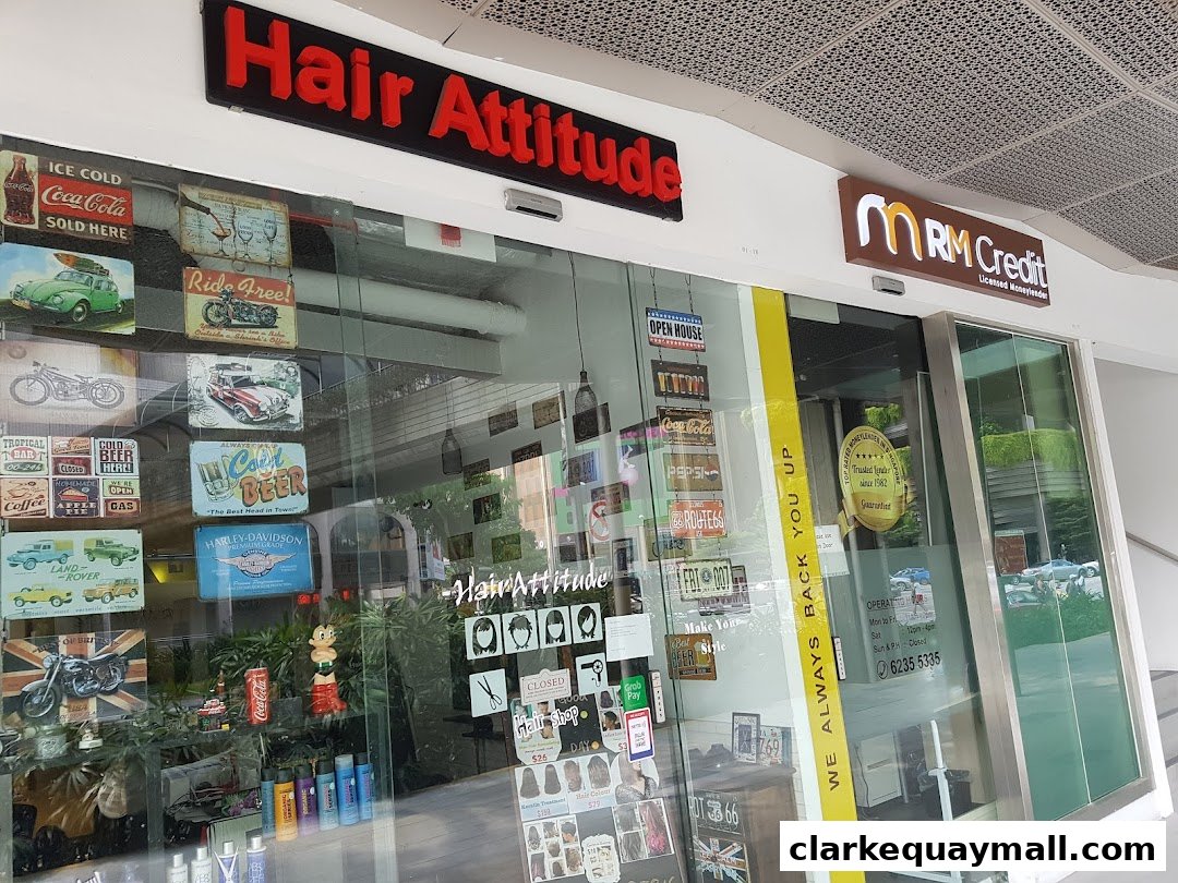 The storefront of Hair Attitude, a hair salon, decorated with vintage signs and displaying hair products.