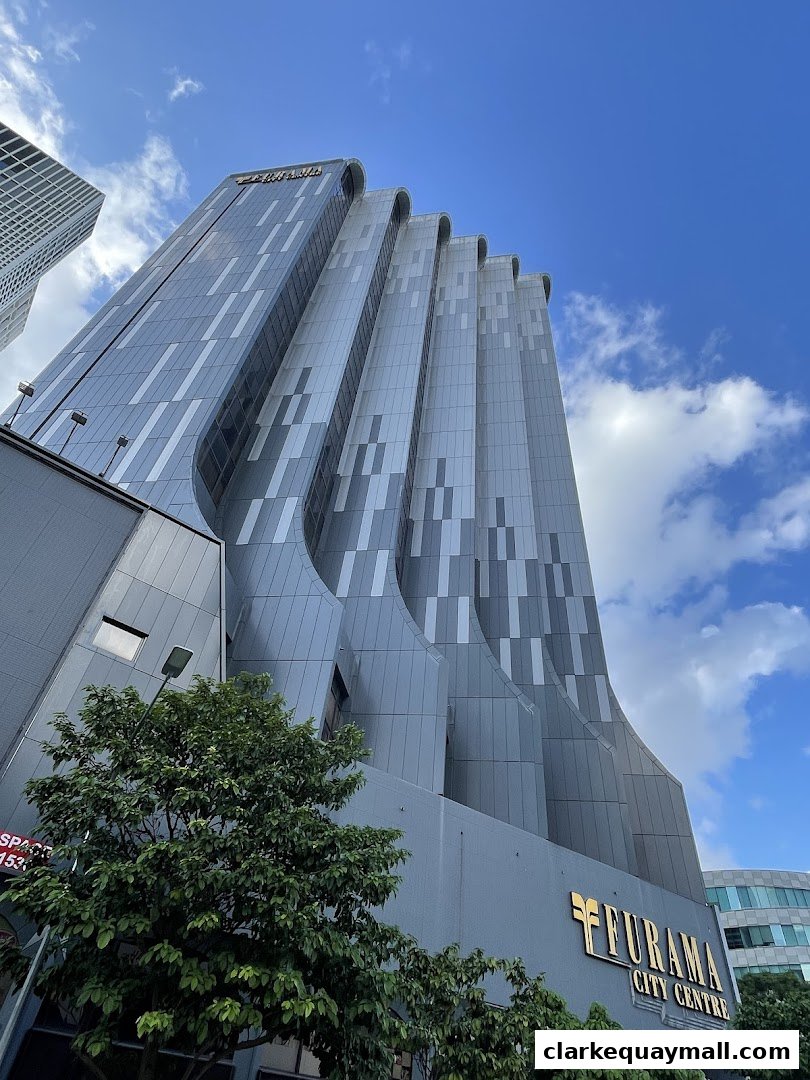 A modern skyscraper with a distinctive curved facade against a blue sky with clouds.