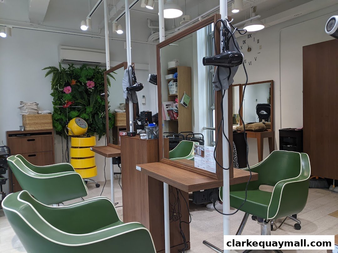 Interior of a modern hair salon with green chairs, mirrors, and hair styling equipment.