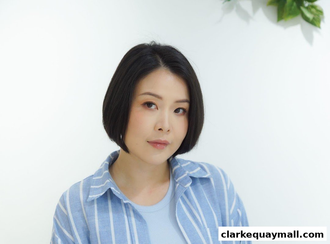 A woman with a short bob haircut and a blue and white striped shirt.