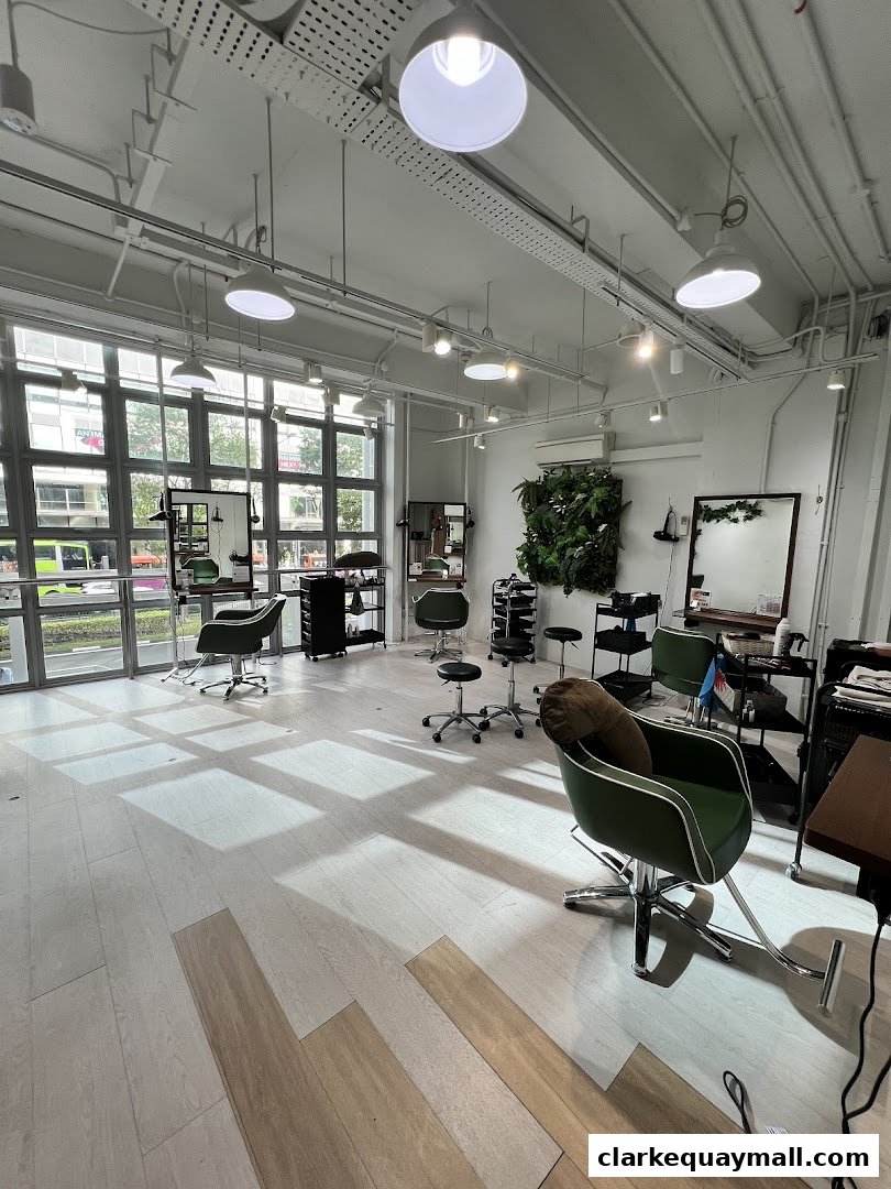 Interior of a modern hair salon with styling chairs, mirrors, and a green wall.