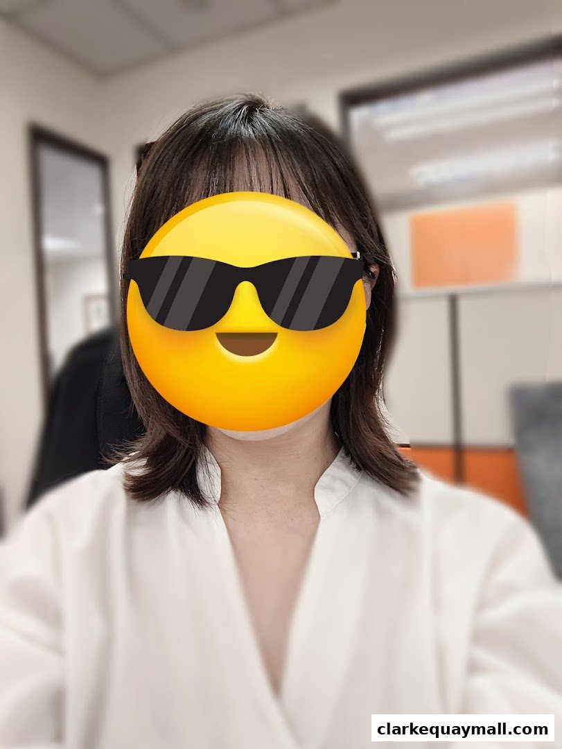 A person with a yellow emoji covering their face, wearing a white top.