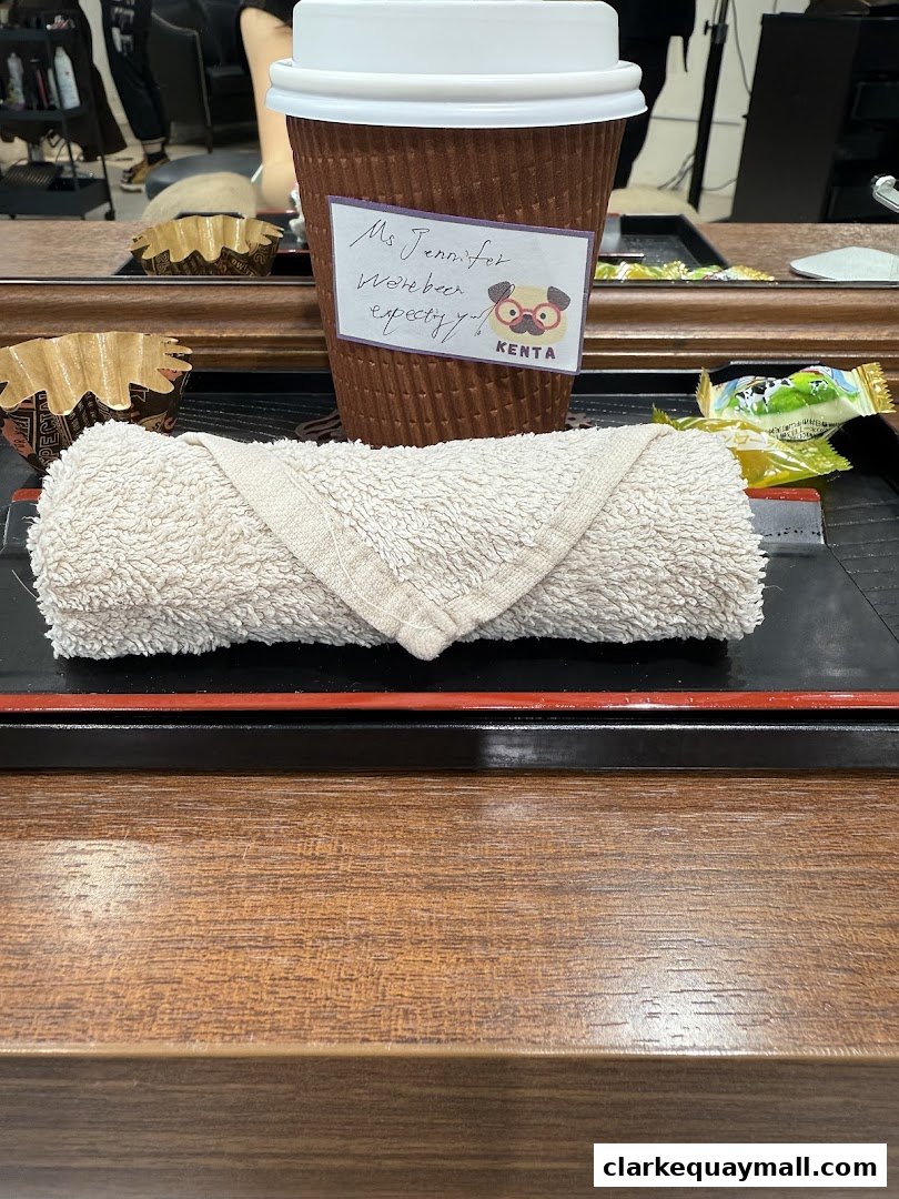 A coffee cup with a personalized note and a rolled towel on a tray.