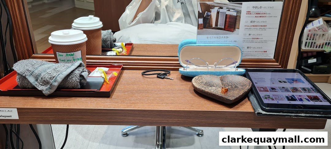 A salon station with drinks, towels, glasses, keys, and a tablet displaying various content.
