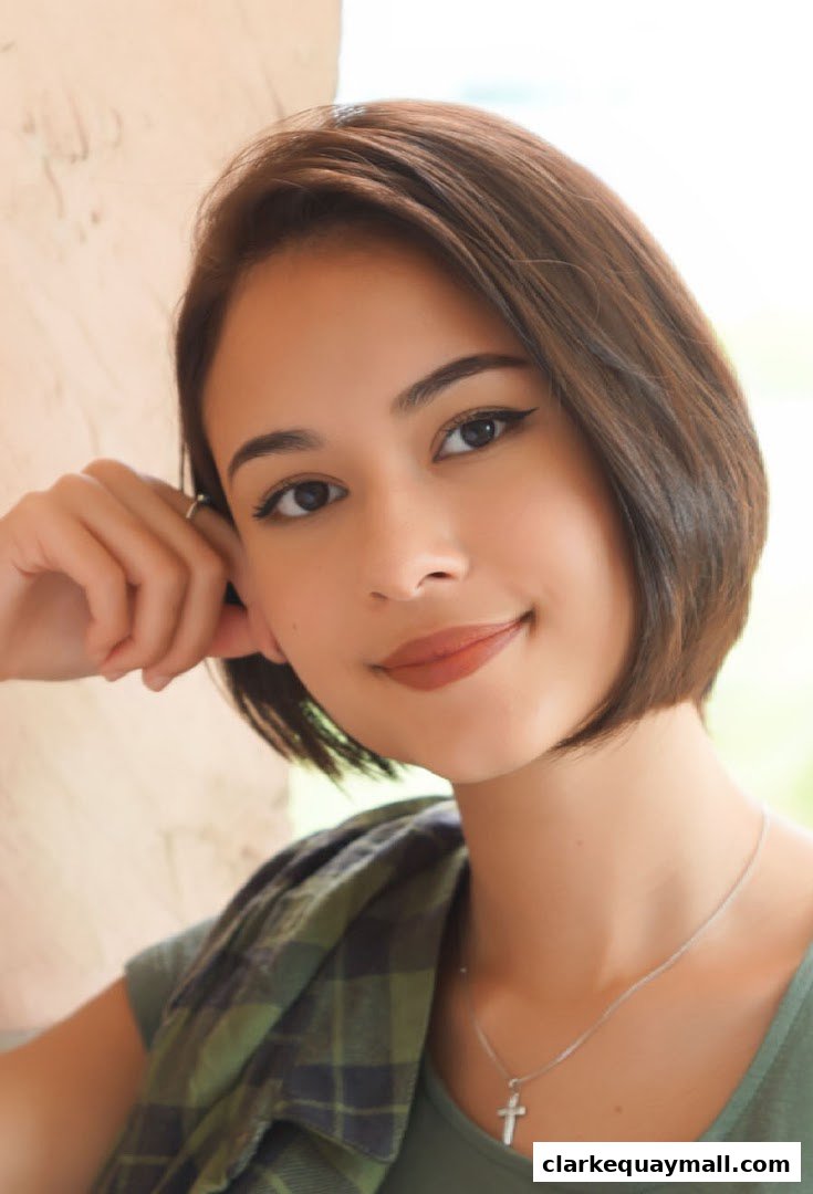 A young woman with a bob haircut and a plaid shirt smiles gently.