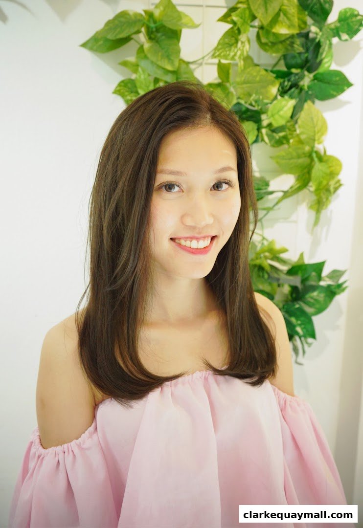 A smiling woman with long, brown hair and a pink off-the-shoulder top.
