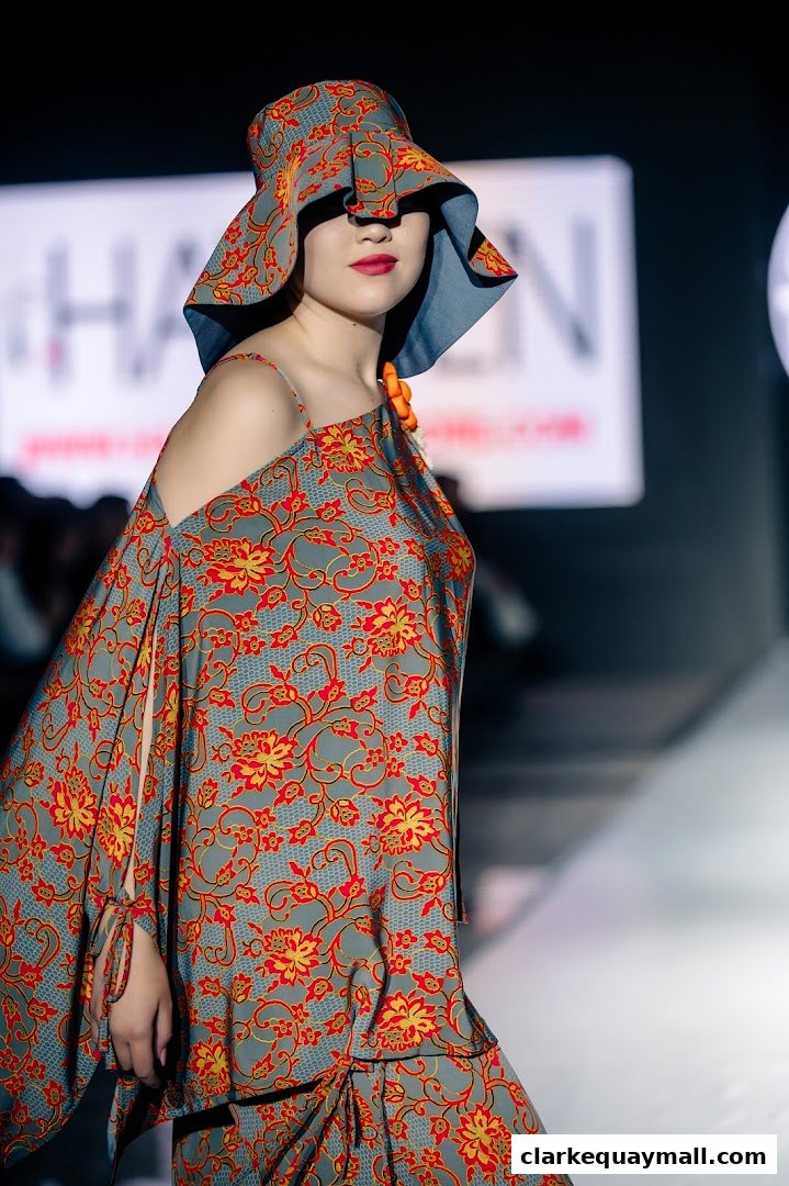 A model showcases a floral print outfit and hat from HAYDEN Boutique on a runway.