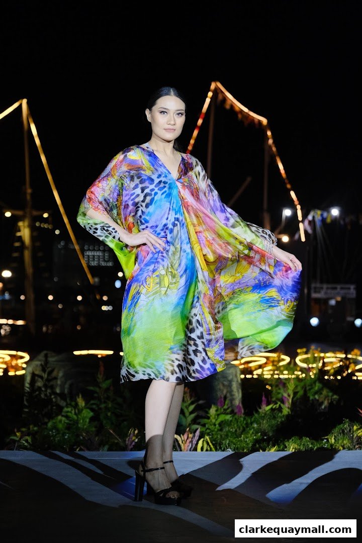 A model poses in a vibrant, flowing kaftan dress with a bold animal print at night.