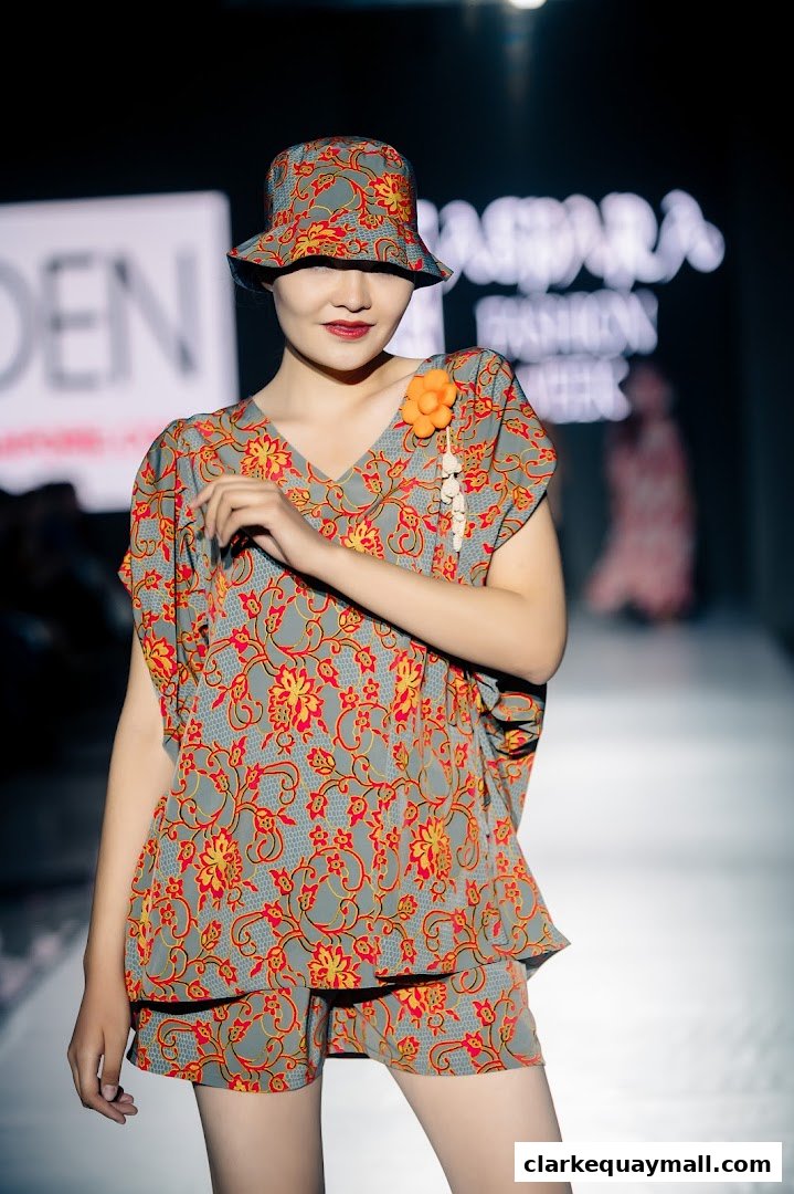 A model showcases a stylish floral print outfit and matching hat on a runway.