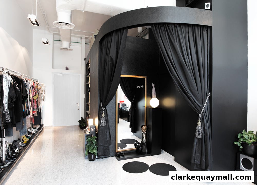 Interior of a stylish boutique with clothing racks, a fitting room, and a large mirror.