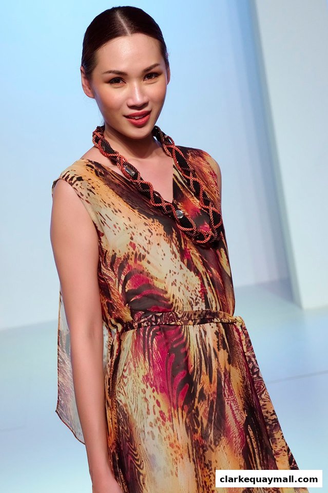 A model showcases a flowing dress with a bold animal print and statement necklace.