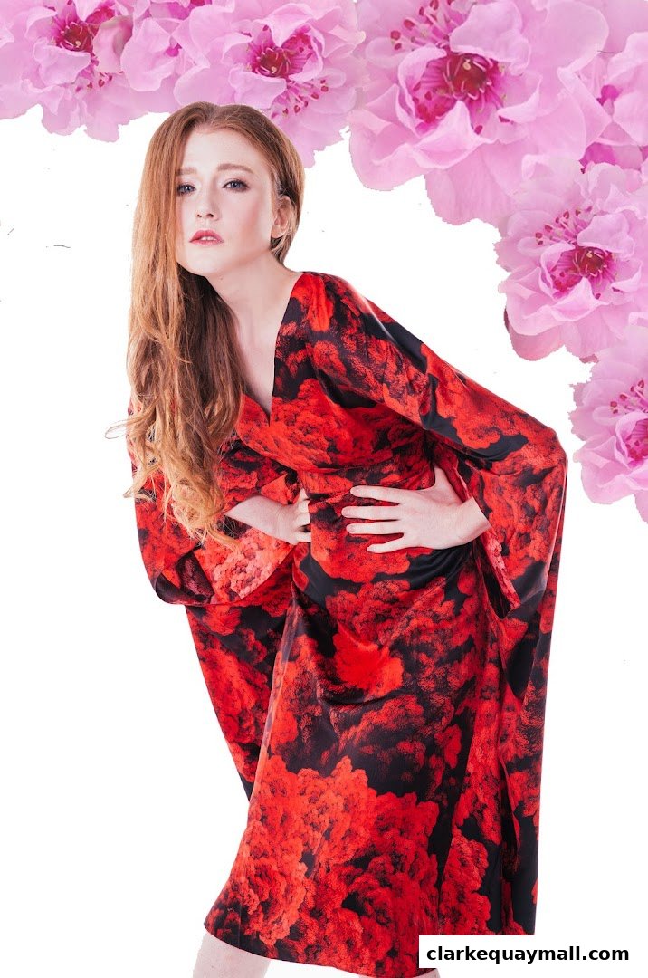 A woman models a vibrant red and black floral print kimono-style dress with pink flowers.