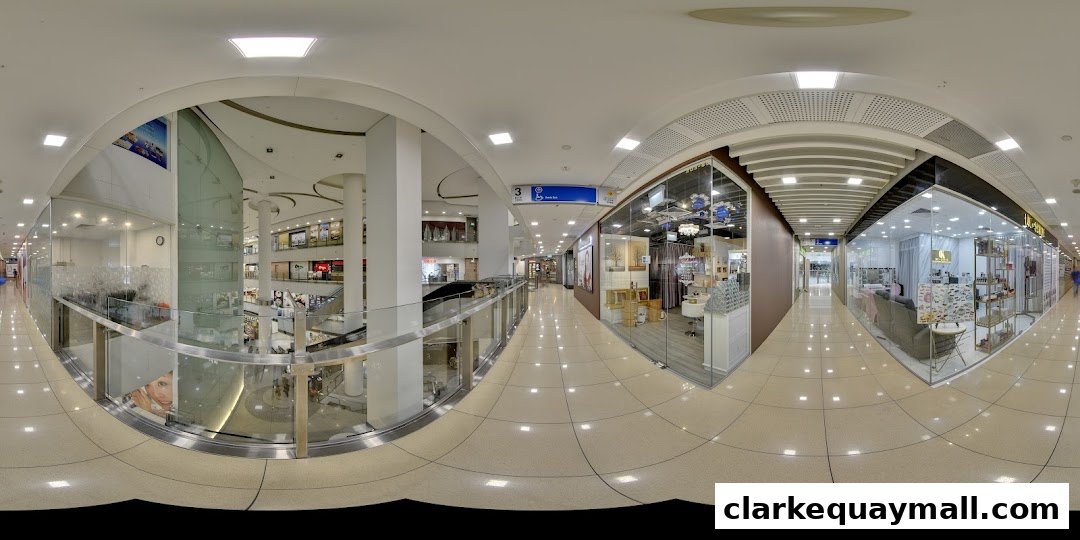 A panoramic view of a modern shopping mall interior with various shops and escalators.