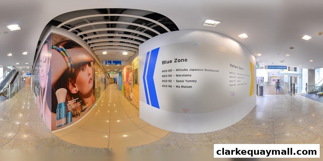 A wide-angle view of a shopping mall corridor with large advertisements and directional signage.