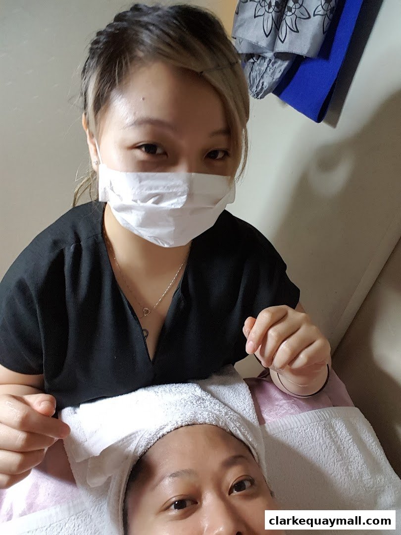 A spa professional in a mask performs a facial treatment on a client.