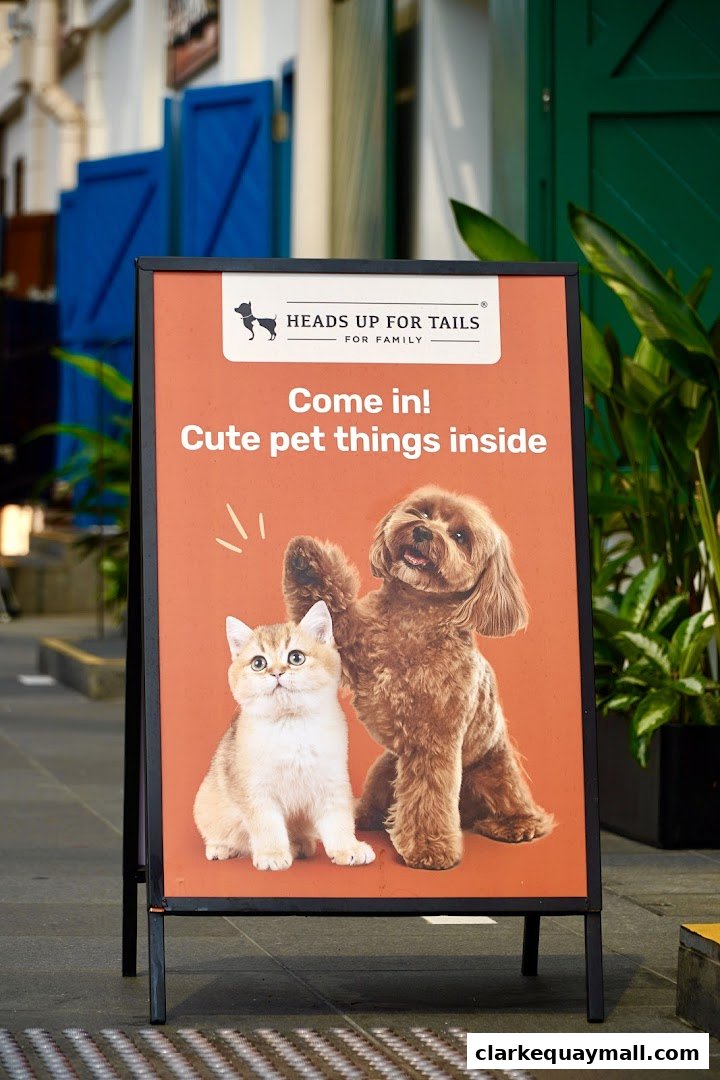 A-frame sign for Heads Up For Tails featuring a dog and cat with text 'Come in! Cute pet things inside'.