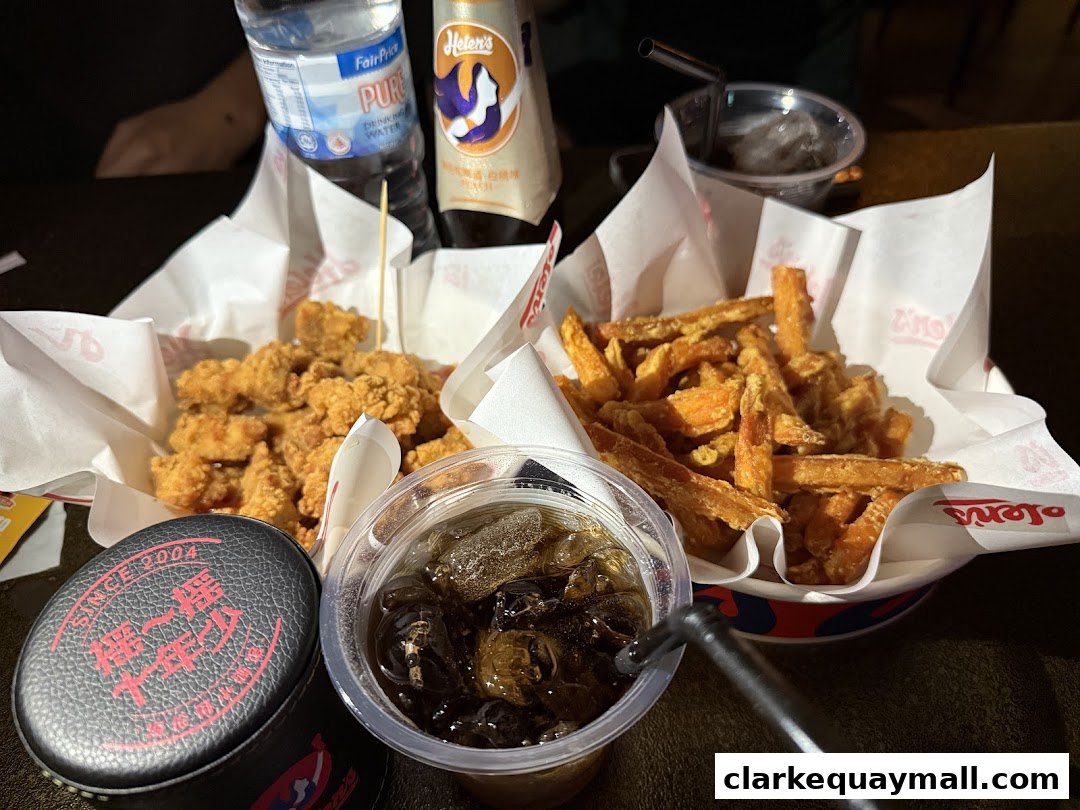 A table filled with fried chicken, sweet potato fries, and drinks from Helens Bar.