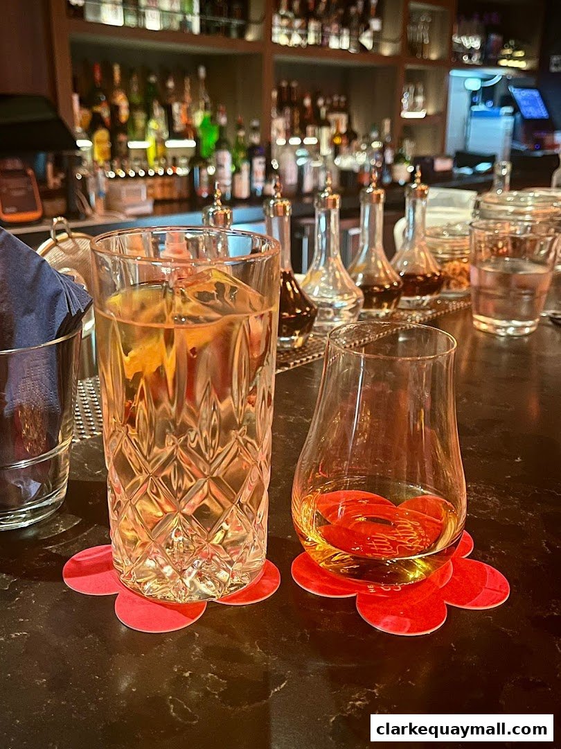 Two cocktails on a bar counter with a blurred background of bottles and bar equipment.