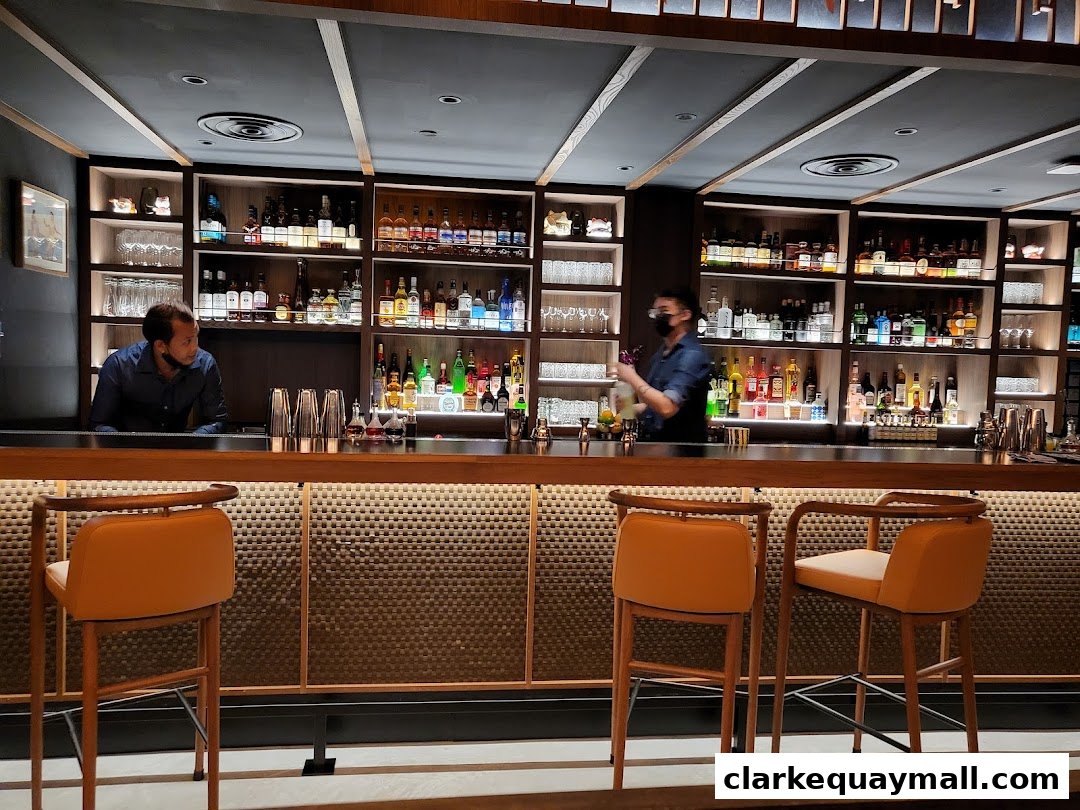 Bartenders prepare drinks behind a well-stocked bar with shelves of liquor and cocktail shakers.